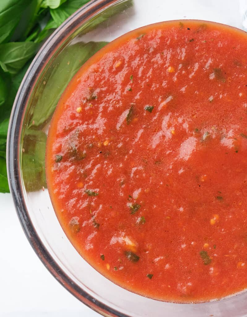 Top view of a glass bowl filled with easy, shiny pizza sauce made with canned tomatoes.