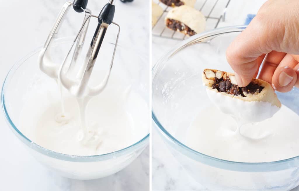 A hand dipping a fig cookie into a bowl full of white royal icing.