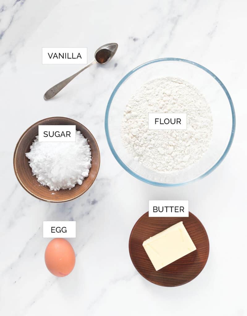 The ingredients to make the shortcrust pastry are arranged over a white background.