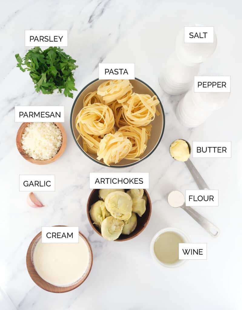 The ingredients to make pasta with artichokes are arranged over a white background.