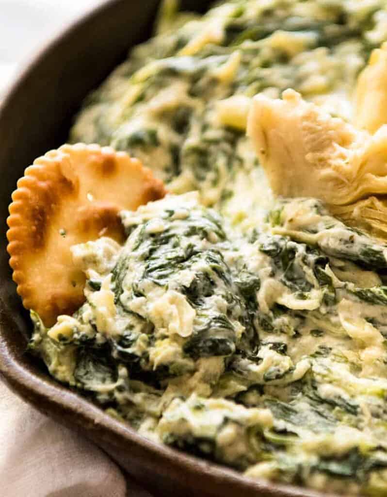 Close-up of a bowl full of soft and creamy artichoke and spinach dip.