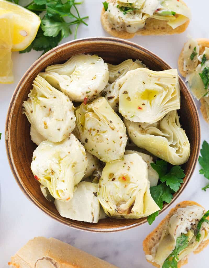 Top view of a brown bowl full of marinated artichoke hearts.