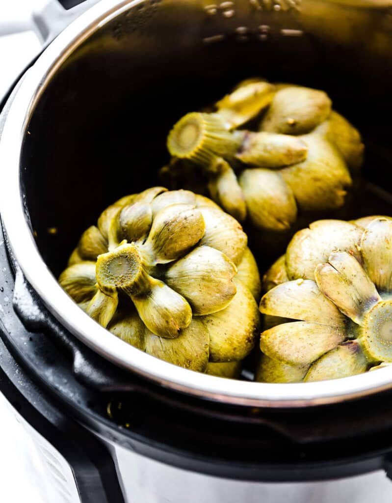 Close-up of an instant pot full of fresh artichokes.