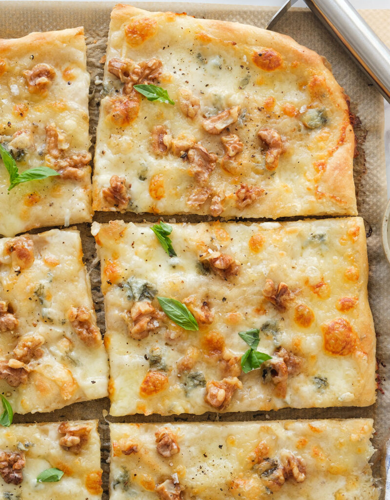 Top view of a large pizza with Gorgonzola cut into slices.