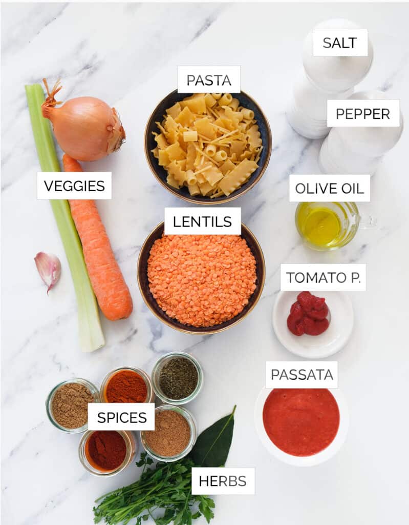 Top view of the ingredients to make red lentil pasta recipe are arranged over a white background.