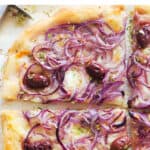 Top view of a large onion pizza cut into slices.