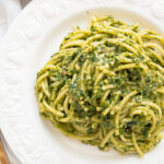 Top view of a white plate full of arugula pasta.