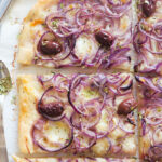Top view of an onion pizza with black olives.