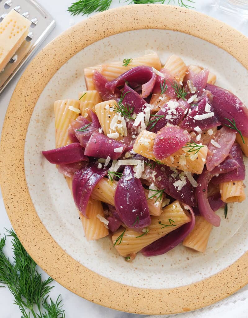 Top view of a plate with pasta with caramelised onions and parmesan.