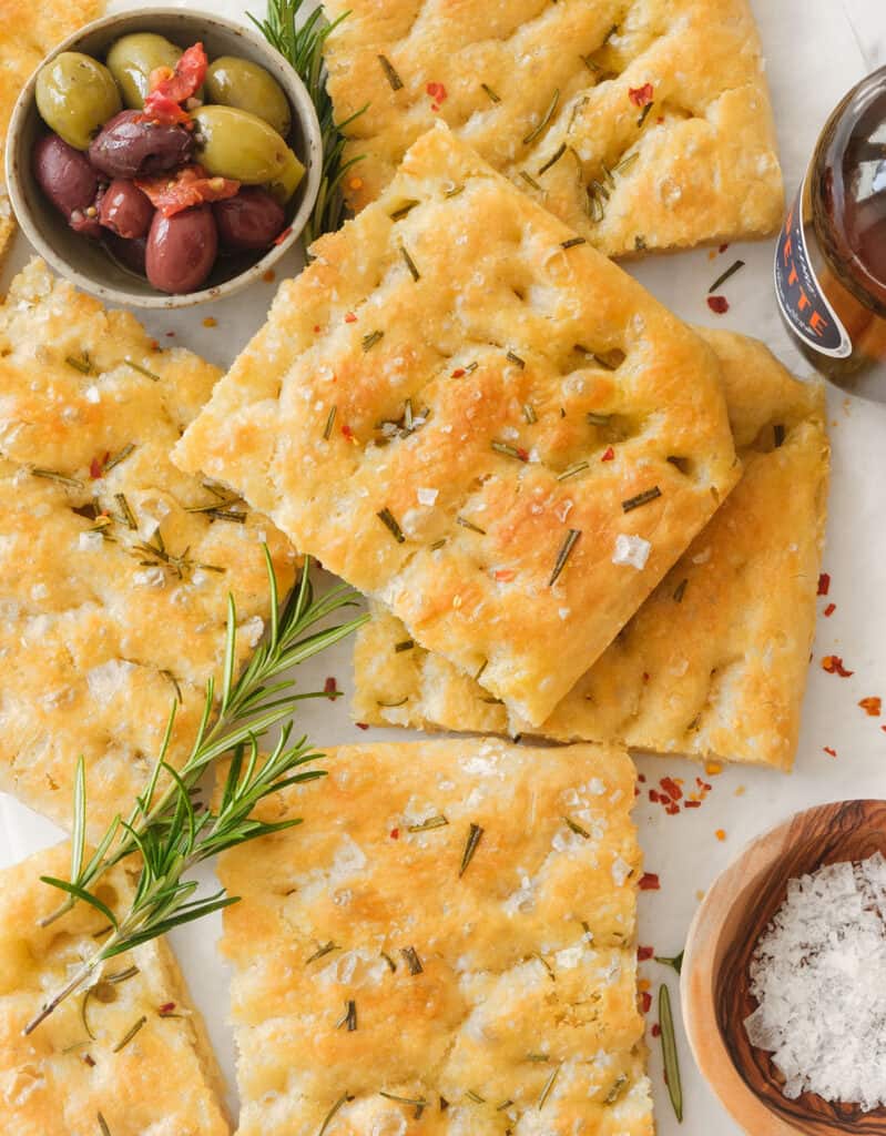 Top view of an easy focaccia with rosemary cut into slices and served with olives.