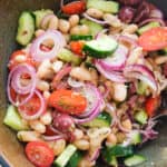 Top view of a large bowl full of Mediterranean bean salad with tomatoes and cucumber.