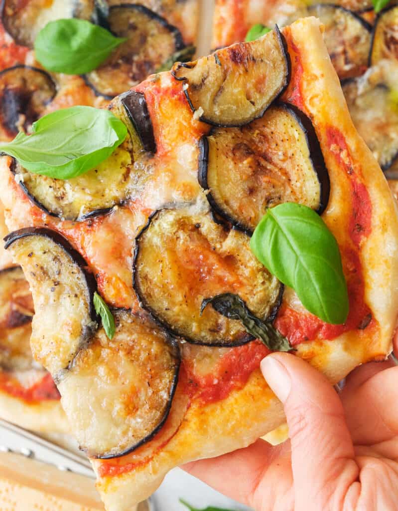 Top view of a slice of pizza with eggplant with creamy mozzarella and basil.