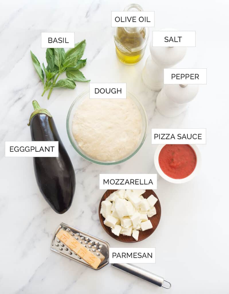 The ingredients to make pizza with eggplant are arranged over a white background.