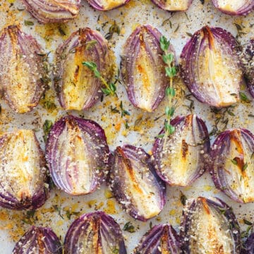 Top view of a baking sheet full of crispy onion wedges roasted with thyme.