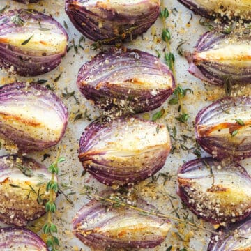 Top view of a baking pan full of roasted onions with crispy breadcrumbs and thyme.