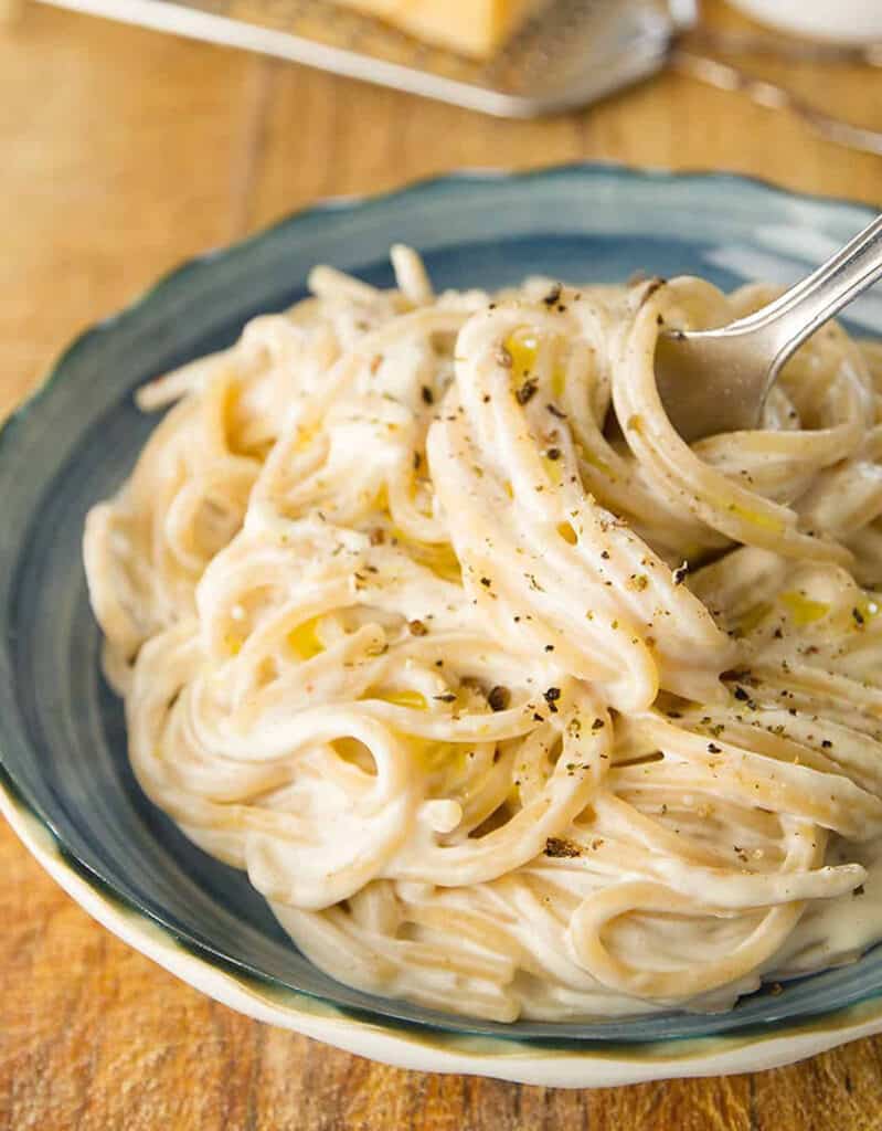 Close-up of a blue plate full of spaghetti with cream cheese sauce.