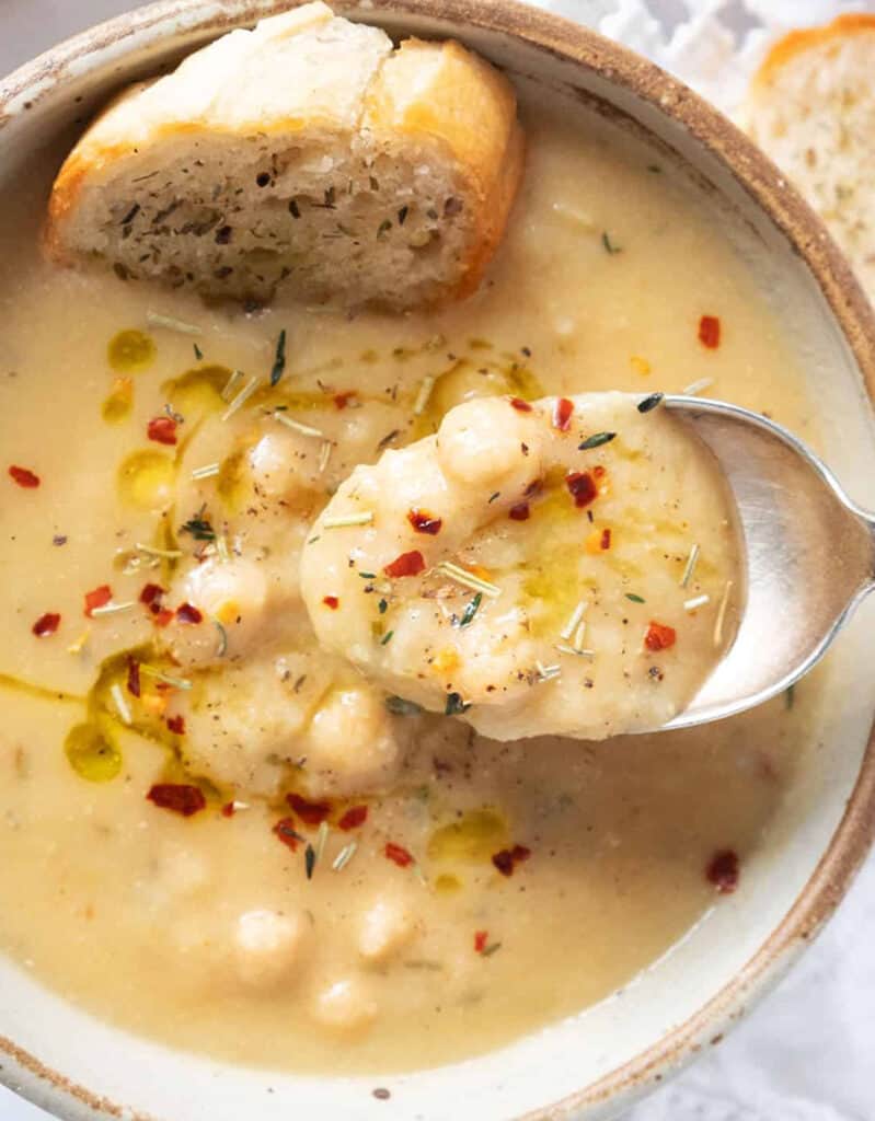 Top view of a bowl full of creamy chickpea soup with crusty bread.