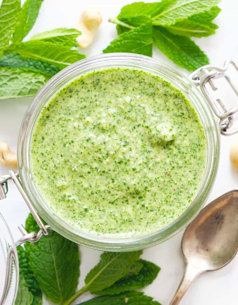 Top view of a glass jar full of bright green mint pesto.