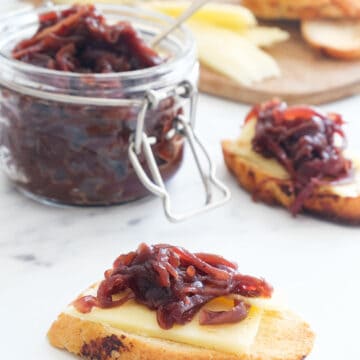 Crusty bread with cheese and onion chutney over a white background.
