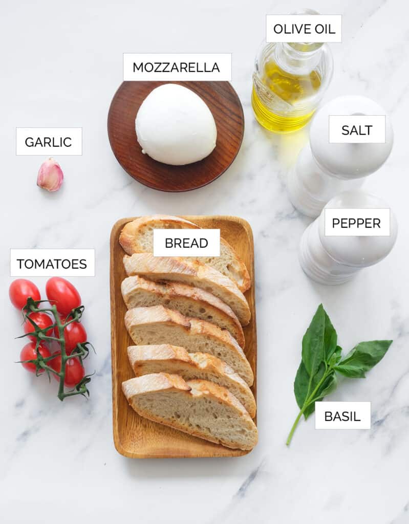 The ingredients to make bruschetta with mozzarella are arranged over a white background.