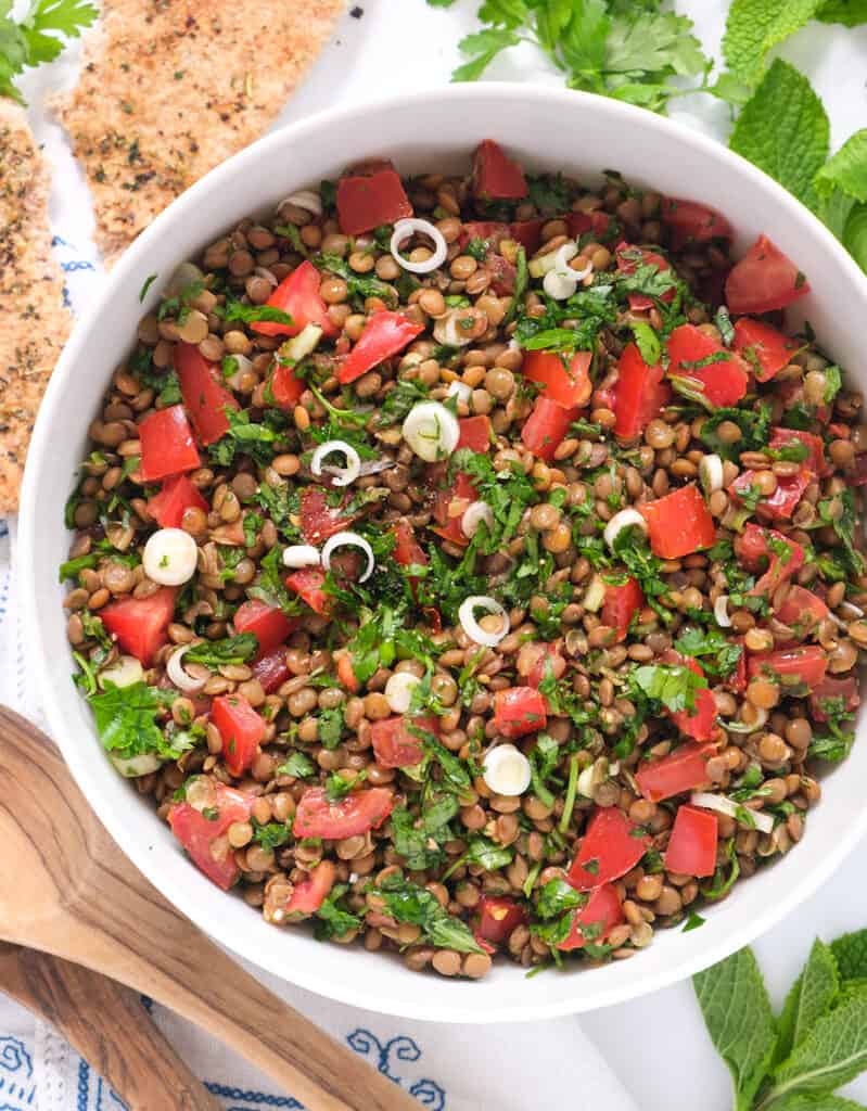 Top white bowl full of lentil tabbouleh with diced tomatoes and parsley.