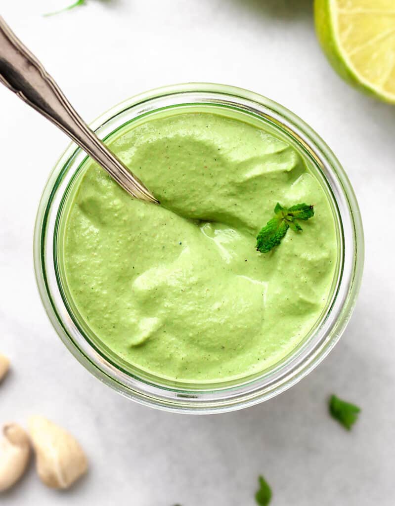 Top view of a glass jar full of creamy mint sauce made with mint and cashews. 