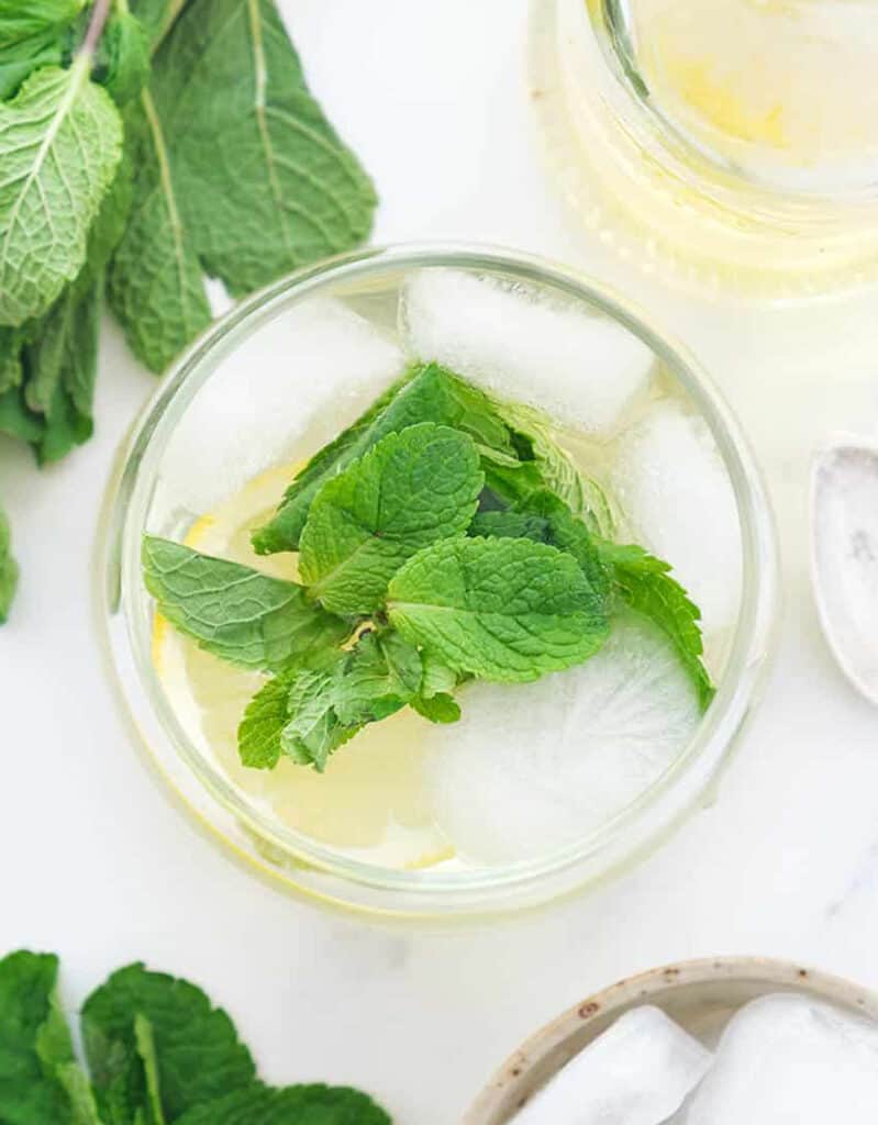 Top view of a glass full of mint syrup, mint leaves and ice.
