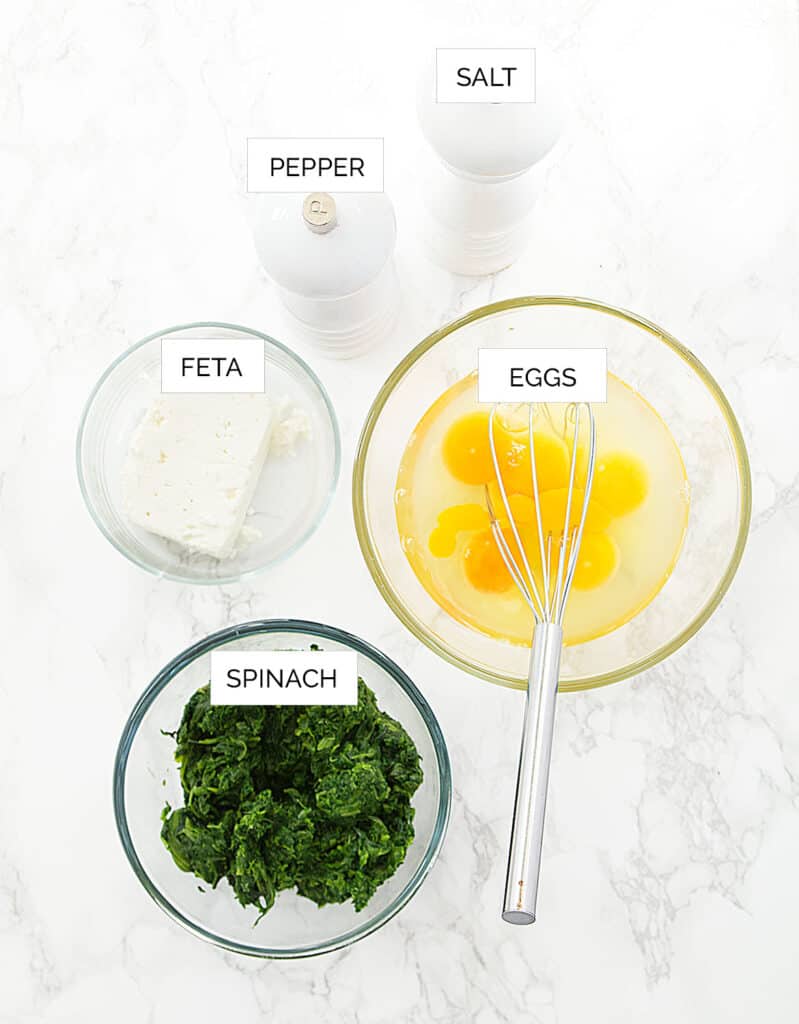 Top view of the ingredients to make a spinach frittata. White surface in the background.