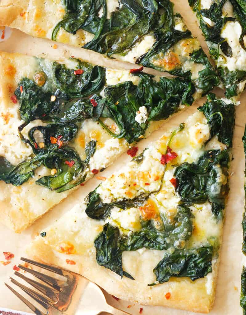 Close-up of a few slices of yummy and moist spinach pizza with mozzarella and feta.