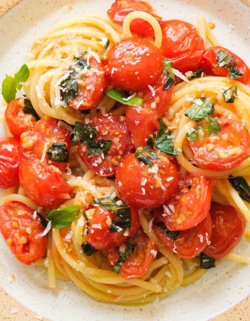 Close-up of a plate full of tomato basil pasta with parmesan cheese.