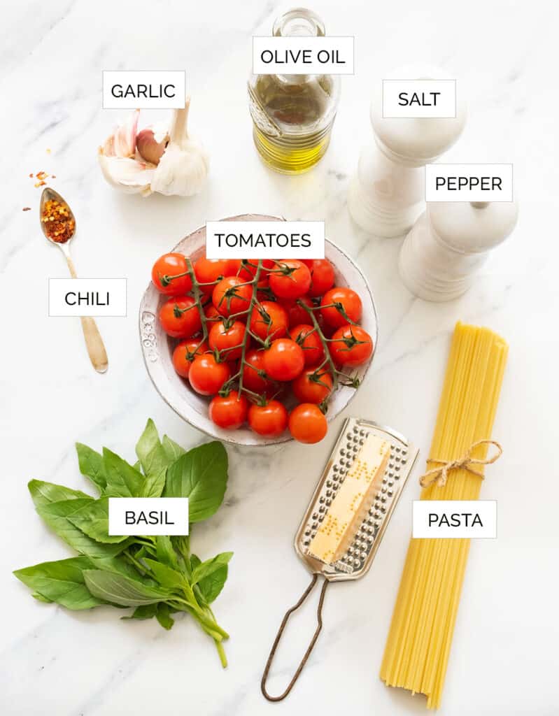 The ingredients to make this tomato basil pasta are arranged over a white background.