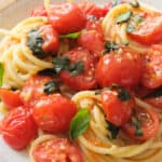 Close-up of a plate full of juicy tomato basil pasta.