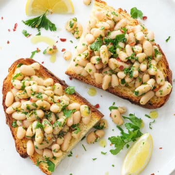 Top view of two crispy slices of bread and beans over a white large plate.
