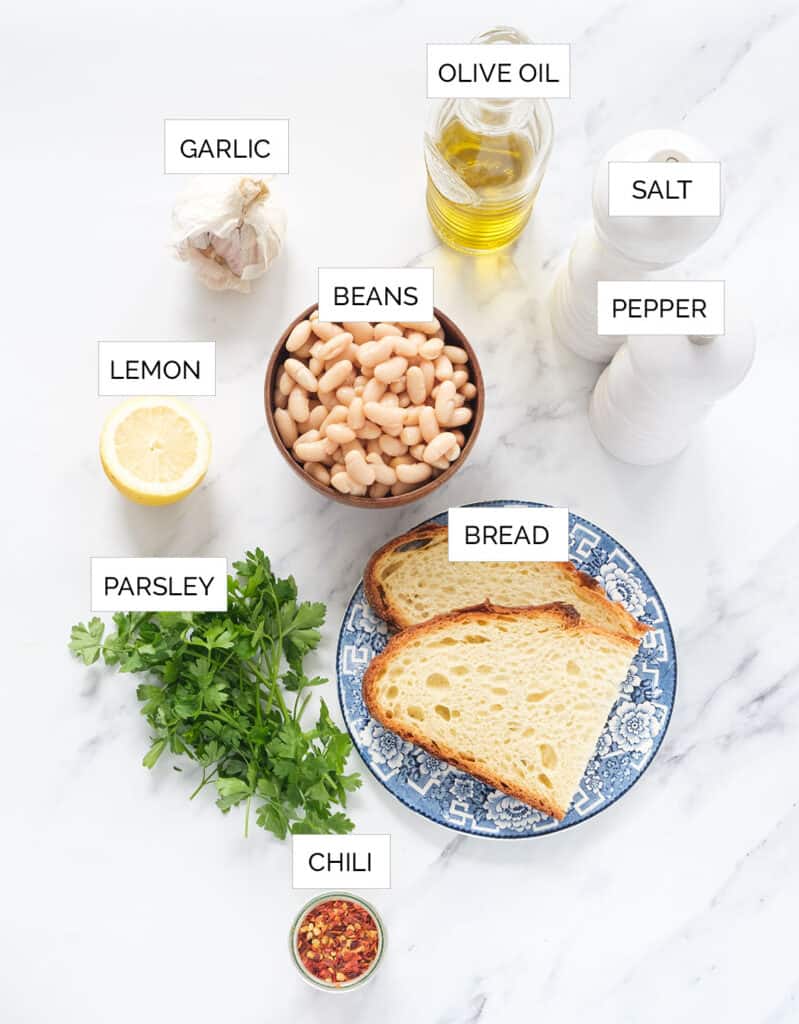 Top view of the ingredients to make bread and beans over a white background.