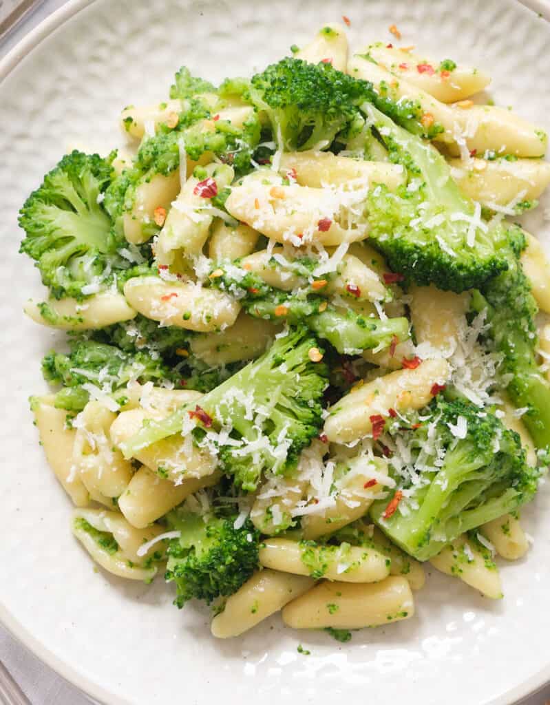 Top view of a white plate full of cavatelli with broccoletti.