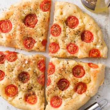 Top view of a large round focaccia with tomatoes.