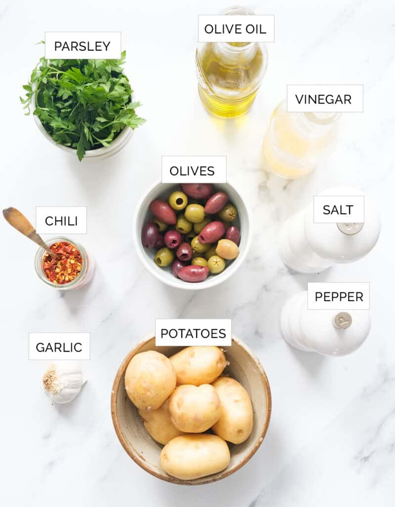 The ingredients to make this salad with olives are arranged over a white background.