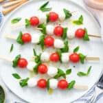 Top view of a white serving plate with caprese salad skewers.
