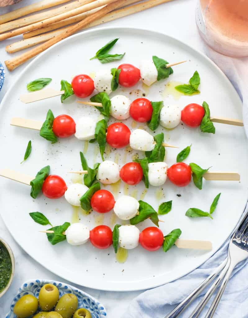 A large white serving plate with caprese salad skewers.