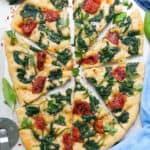 Top view of a scrumptious focaccia topping made with spinach and sun dried tomatoes.