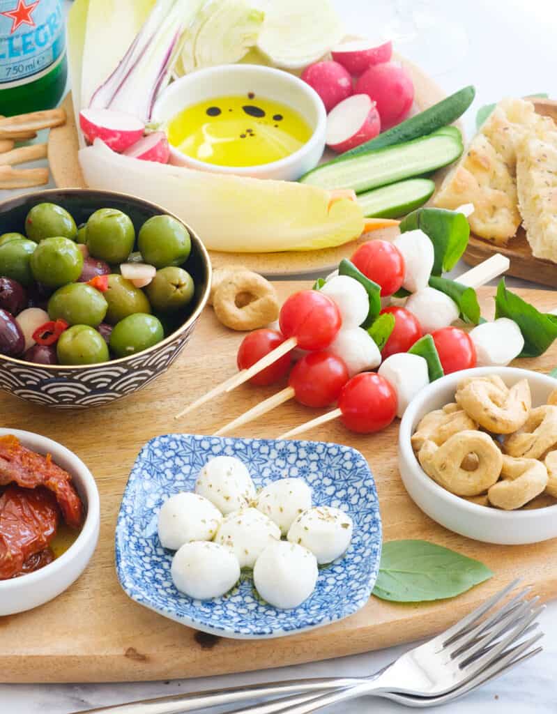 Close-up a table full of Italian appetizers including mozzarella, caprese skewers, and pinzimonio.