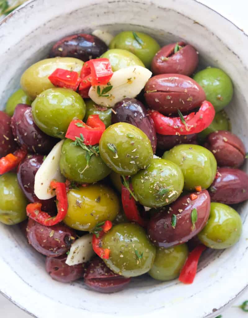 Close-up of the spicy olives showing the marinade made with olive oil, chili and herbs. 