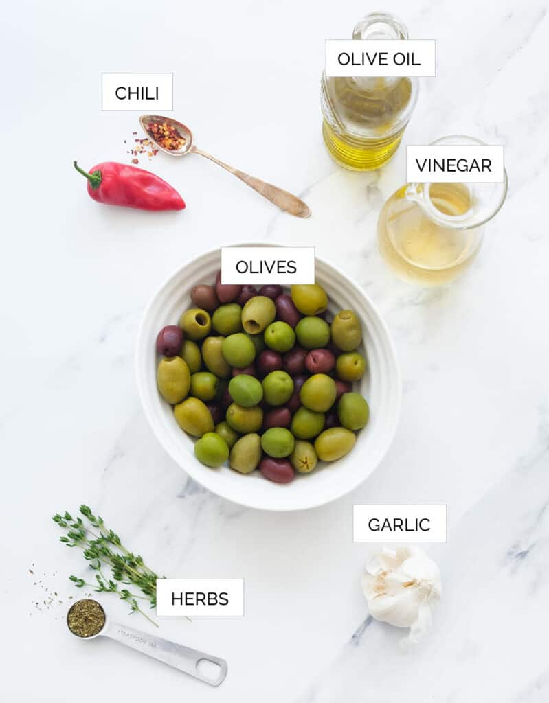 Top view of the ingredients to make these spicy olive over a white background.
