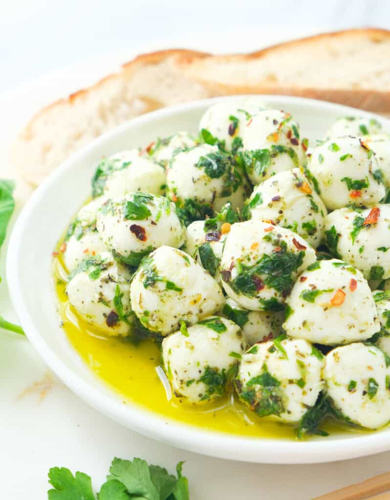 Close-up of some marinated mozzarella balls on a white plate.