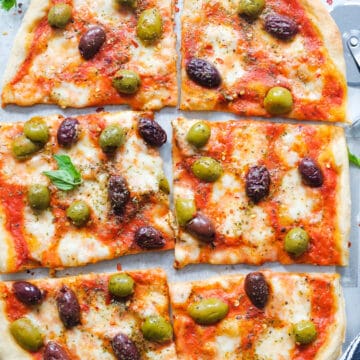 Top view of a large olive pizza cut into slices.