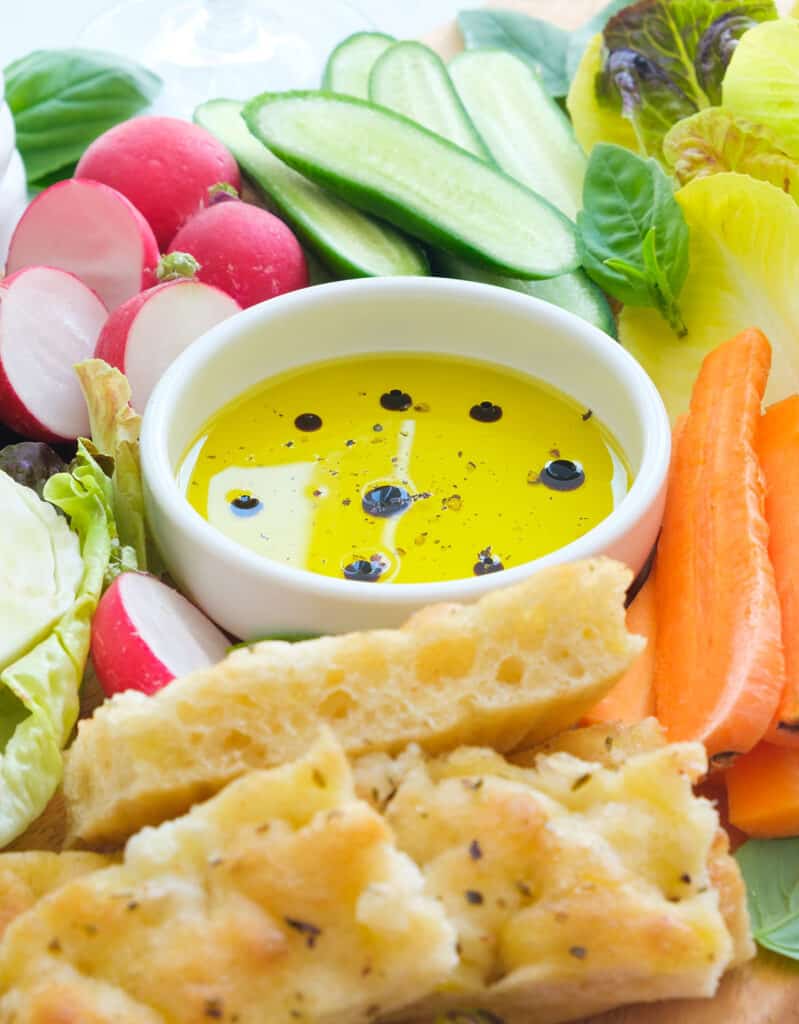 Close-up of a small white bowl with pinzimonio served with crudités and focaccia.