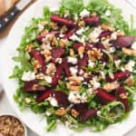 Top view of a white serving plate full of beet salad with feta.