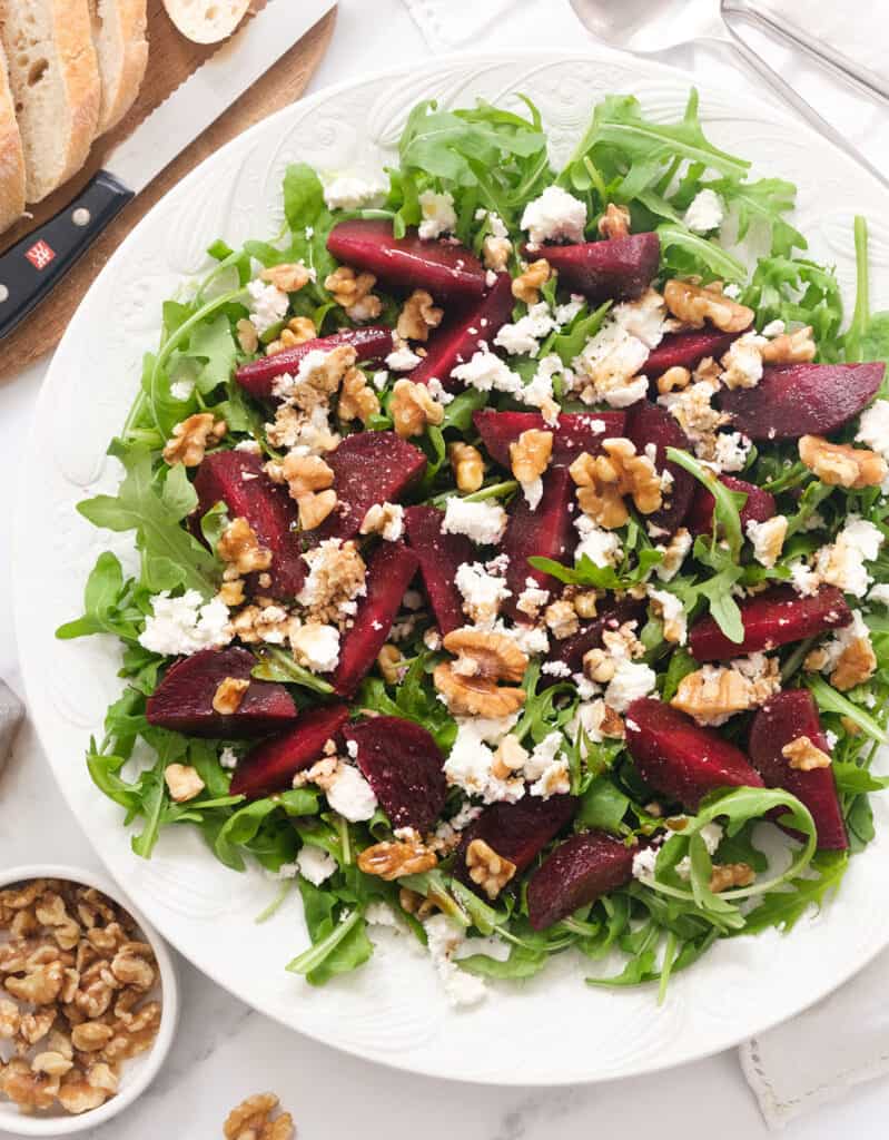 Top view of a white salad plate full of beet salad with feta and arugula.