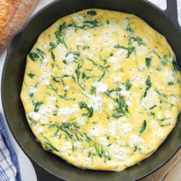 Top view of a cast iron skillet with arugula frittata.