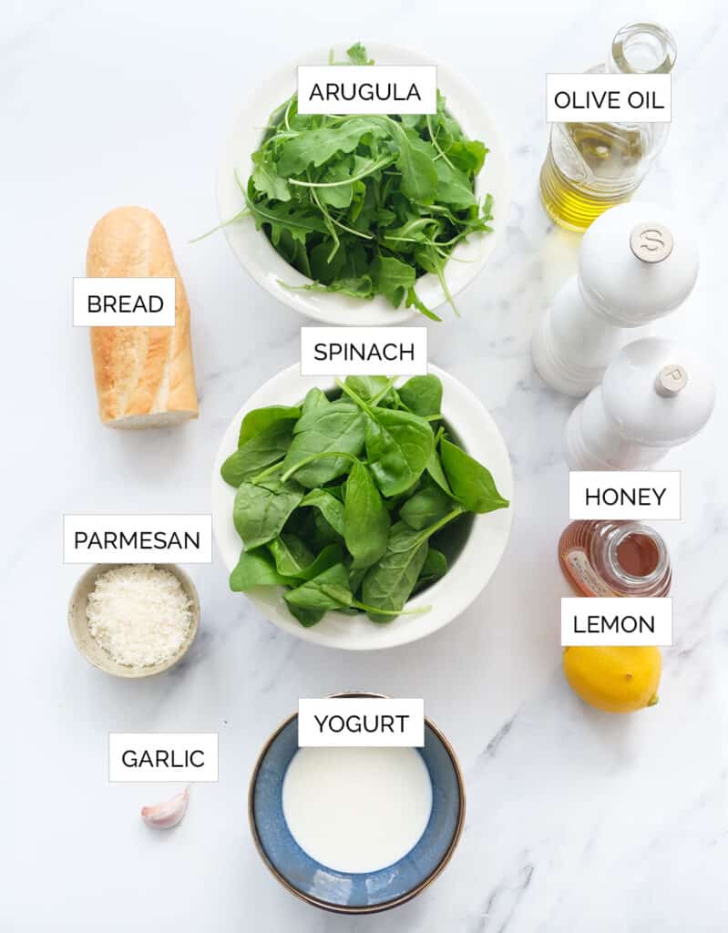The ingredients to make this spinach arugula salad are arranged over a white background.